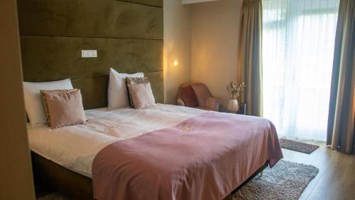 a bedroom with a large bed with pink sheets and pillows at Schaluinenhoeve in Baarle-Nassau