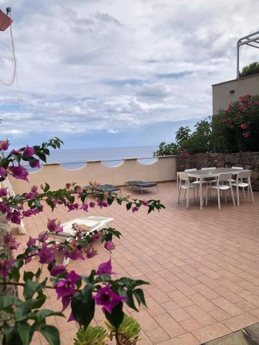 a patio with tables and chairs and purple flowers at Casa Rais Dragut in Capraia