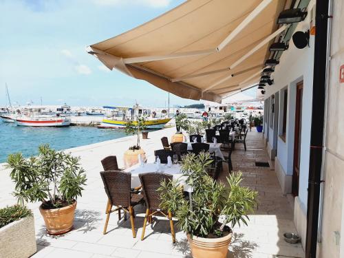 a restaurant with tables and chairs and boats in the water at Villa Elizej in Fažana