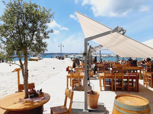 a beach with tables and chairs and a white umbrella at Villa Elizej in Fažana