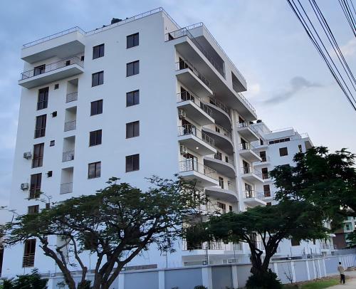 a white apartment building with trees in front of it at Luxury 3br Ensuite Apt in Prestigious Nyali in Mombasa