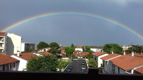 un arco iris sobre una ciudad con casas y una calle en FLEURI, en Anglet