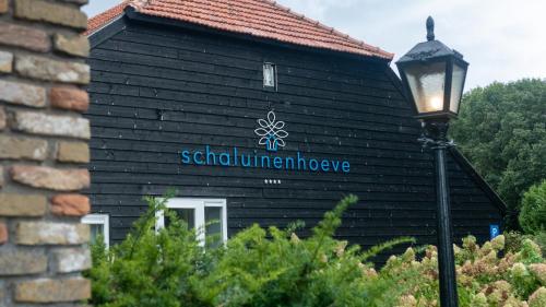 a black building with a sign on it at Schaluinenhoeve in Baarle-Nassau