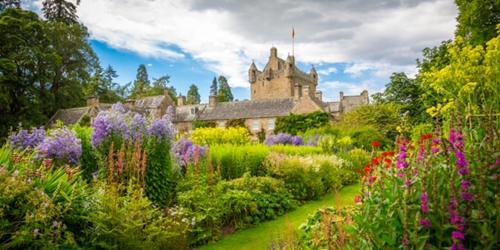 a garden with flowers in front of a castle at The Roost in Aviemore