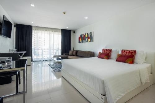 a bedroom with a large white bed and a living room at Citismart Luxury Apartments in Pattaya Central