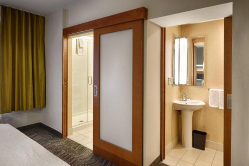 baño con cama, lavabo y puerta en SpringHill Suites by Marriott Albany Latham-Colonie, en Albany