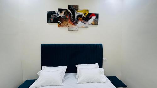 a bed with two pillows and a painting on the wall at Home Escape Luxé Private Villa- Indralaya in Ujjain