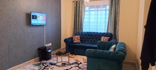 sala de estar con sofá azul y 2 sillas en Lux Suites Cavendish Square Apartments, en Syokimau