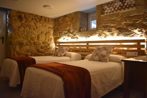 two beds in a room with a stone wall at Casa da Aldea A Fonte - Meaño in Santa Cristina