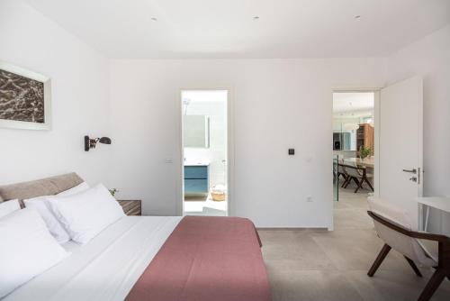 a white bedroom with a bed and a dining room at Villa Inati in Nípos