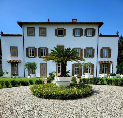 a large white house with a palm tree in front of it at LA VILLA APARTMENTS - Convenient for Sardinia and Corsica - 5 beds -Private Parking included with Camera in Livorno