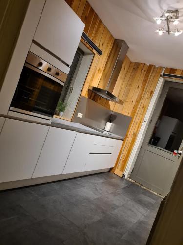 a kitchen with white cabinets and a sink and a door at "Petit Durbuy" by Phils Cottages in Durbuy