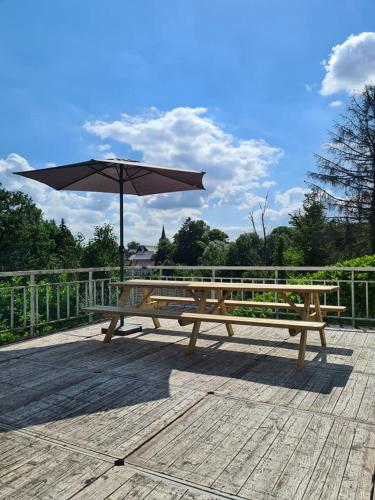 a wooden picnic table with an umbrella on a deck at "Petit Durbuy" by Phils Cottages in Durbuy