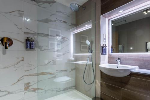 a bathroom with a shower and a sink and a mirror at Auchrannie Resort in Brodick