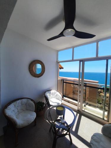 een woonkamer met een plafondventilator en uitzicht op de oceaan bij Vista Tabarca in Santa Pola