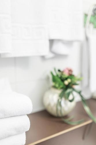 a vase with flowers on a shelf next to towels at Hotel Donatello Imola in Imola