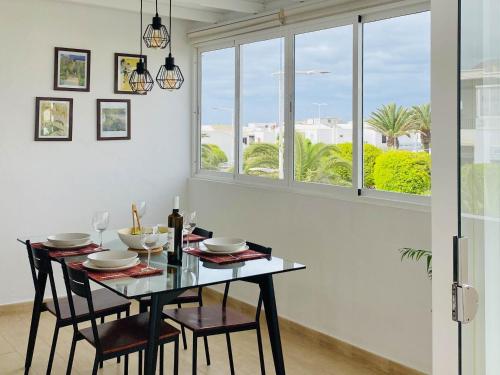 a dining room with a table and chairs and windows at Casa del Mayor in Playa Honda