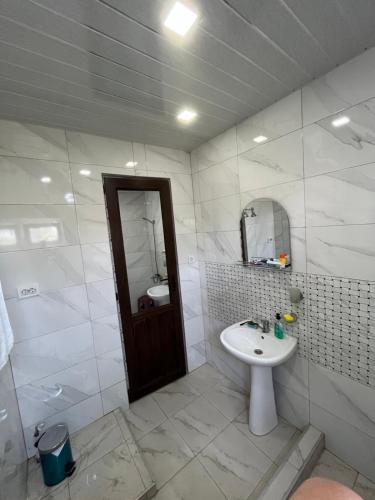a white bathroom with a sink and a mirror at Guesthouse "Kvara"- Mukhuri in Chʼkhorotsqu