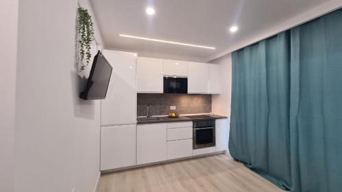 a kitchen with white cabinets and a green curtain at Mariposa Azul in Adeje