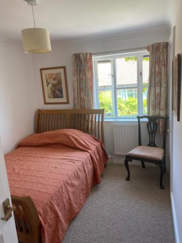 een slaapkamer met een bed, een raam en een stoel bij Goodwood Rooms in Charlton