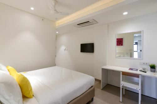 a white bedroom with a bed and a desk at Hotel Centro in Pune