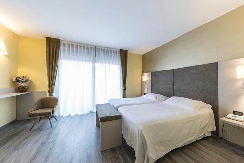 a hotel room with two beds and a window at Hotel Donatello Imola in Imola