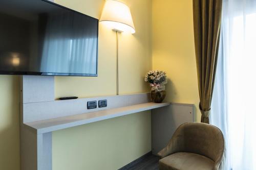a room with a tv and a chair and a mirror at Hotel Donatello Imola in Imola