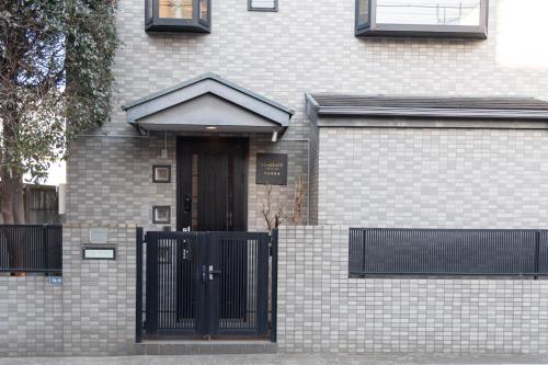 a brick house with a black door and a fence at LiveGRACE Hotel Shibuya 渋谷西新宿 in Tokyo