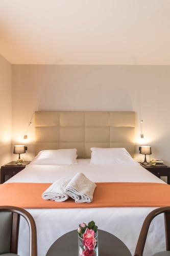 a bedroom with a large bed with two tables and two lamps at Hotel Donatello Imola in Imola