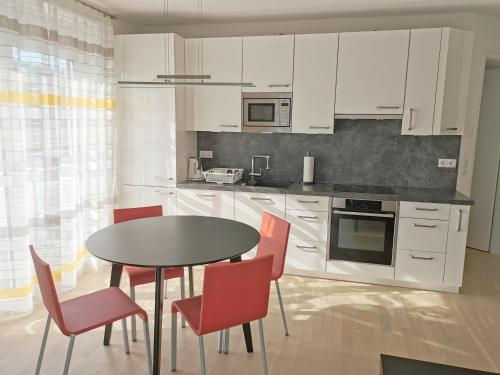 uma cozinha com armários brancos e uma mesa e cadeiras em Ferienwohnung Pinovas em Friedrichshafen