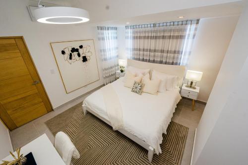 1 dormitorio con 1 cama con sábanas y almohadas blancas en Stunning view of the city., en Santo Domingo