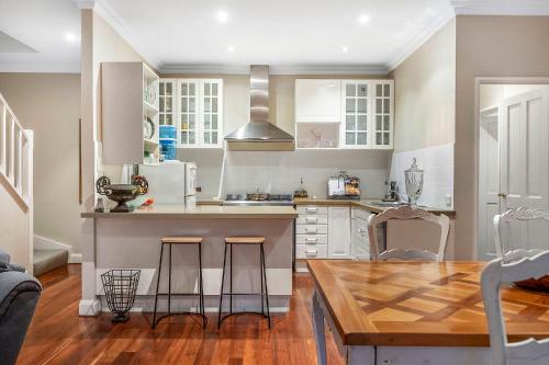 a kitchen with white cabinets and a wooden table at Fremantle Accommodation Villas Arundel St in Fremantle