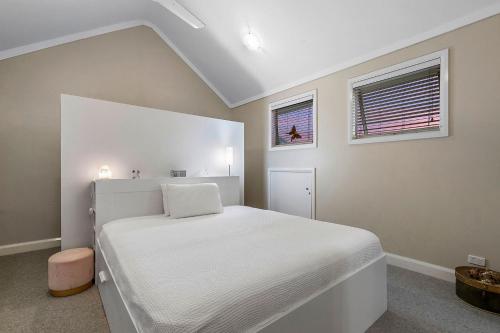 a white bedroom with a white bed and two windows at Fremantle Accommodation Villas Arundel St in Fremantle