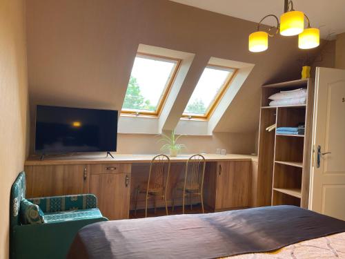a bedroom with a bed and a tv and two windows at Károlyi Panzió in Eger