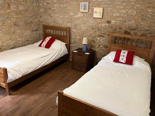 ein Schlafzimmer mit 2 Betten und einem Tisch mit einer Lampe in der Unterkunft La Grange Du Noyer in Cornac