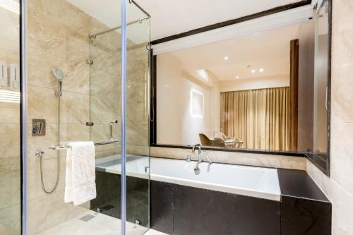 a bathroom with a tub and a glass shower at Dayal Gateway in Lucknow