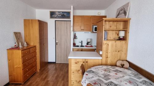 eine Küche mit Holzschränken und ein Bett in einem Zimmer in der Unterkunft Studio 4 personnes à La Rosière in Montvalezan