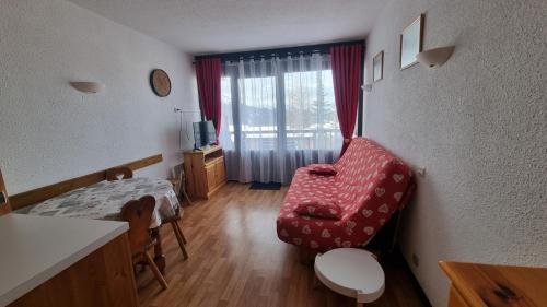 ein Wohnzimmer mit einem roten Stuhl und einem Fenster in der Unterkunft Studio 4 personnes à La Rosière in Montvalezan