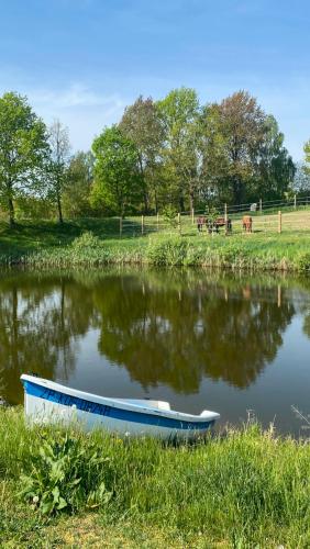 a small boat sitting on the shore of a pond at Pełnikowe Zacisze in Bobolice