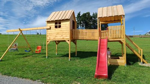 a wooden play structure with a slide and a playground at Jagodowe Domki in Ciche