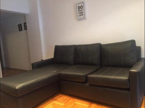 un sofá de cuero negro en una sala de estar con una señal de no fumadores en Apartamento en el corazón de Recoleta en Buenos Aires