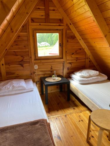 two beds in a wooden cabin with a window at ŻURAWISKO - domki letniskowe Jarosławiec in Jarosławiec