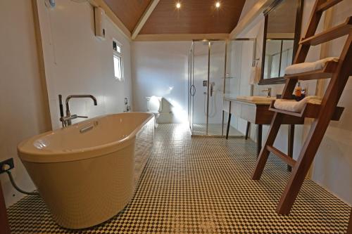 ein Badezimmer mit einer großen Badewanne und einer Dusche in der Unterkunft Manohari The Tea Retreat in Dibrugarh