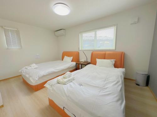 2 bedden in een kamer met witte lakens bij ヴィラ ザ・キューブVilla The Cube Fuji view Annovillas in Fujikawaguchiko