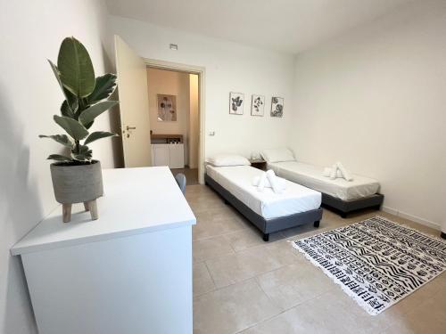 - un salon avec deux lits et une plante en pot dans l'établissement Castramajora Alloggi, à Casalmaggiore