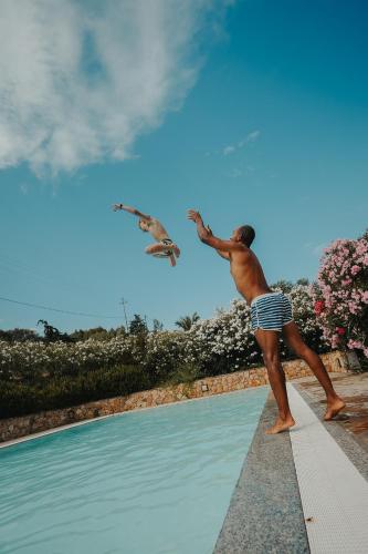 a man flying a bird over a swimming pool at Villa Alba Sul Mare in Budoni