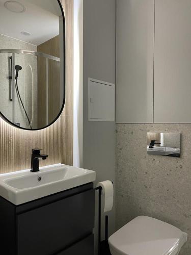 a bathroom with a sink and a toilet and a mirror at Apartament Kasztanowa in Augustów