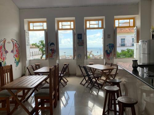 restauracja z drewnianymi stołami, krzesłami i oknami w obiekcie Hostel Morro de Sao Paulo w mieście Salvador