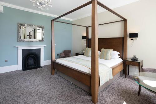 a bedroom with a canopy bed and a fireplace at Barton Hall Hotel & Spa in Kettering