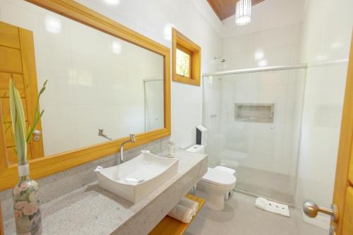 a bathroom with a sink and a toilet and a mirror at Arraial Bangalô Praia Hotel in Arraial d'Ajuda